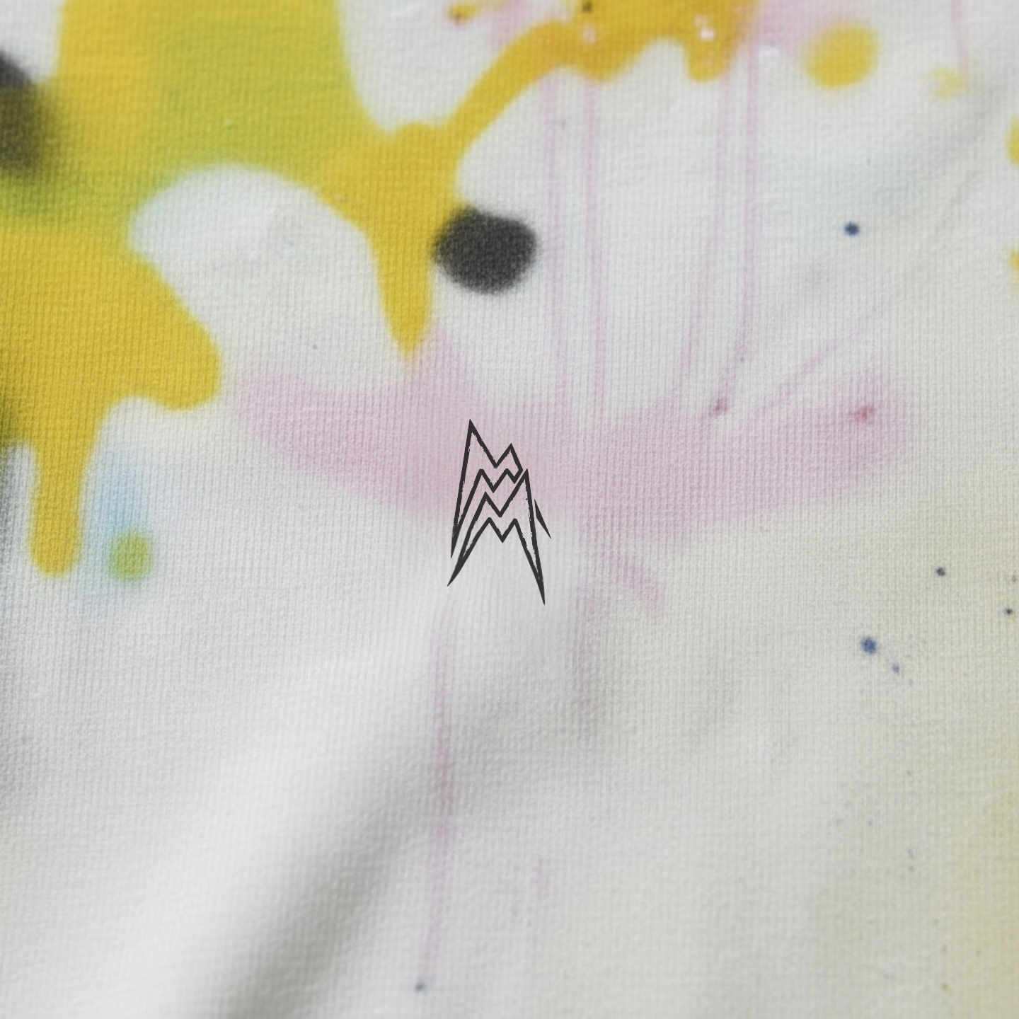 Close-up of a limited edition street couture T-shirt: handmade spray effects and subtle logo in the center of the chest.